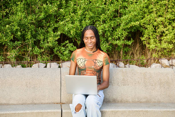 istock Non-binary person working on laptop sitting on a bench in the city. 1793487720