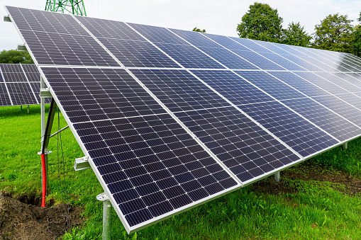 Installation of solar panels on metal frames in a green meadow, unfinished solar power plant, alternative source of electricity