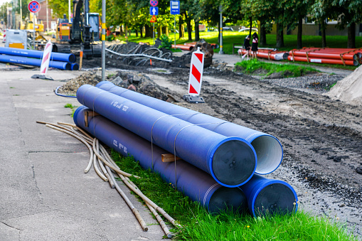 Replacement of underground water supply and sewer pipes in city street, new blue thick plastic water supply pipes in foreground