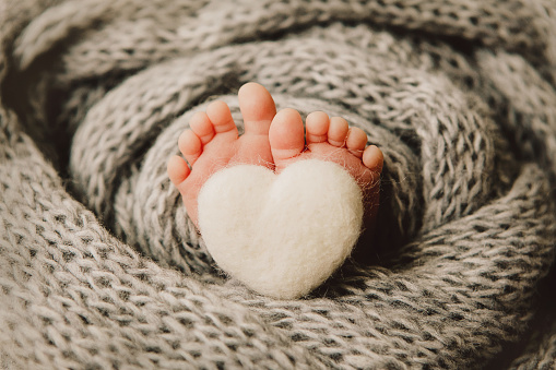Close up crop legs of newborn baby wrapped in warm knitted blanket