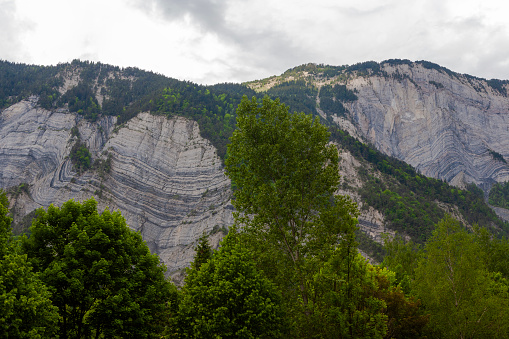Distorted sedimentary rocks in the cliff face overlooking the town of Le Bourg-d'Oisans, Isère department in southeastern France