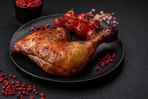 Delicious grilled chicken leg or quarter with salt and spices on dark concrete background