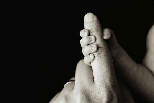 A close up image of a tiny newborn's hand gripping father's finger.