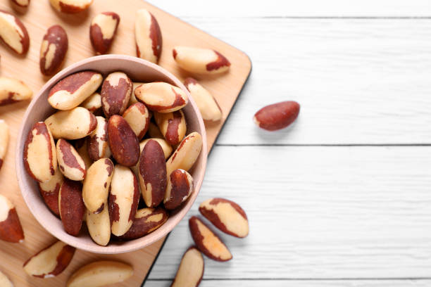 istock Delicious Brazil nuts on white wooden table, flat lay. Space for text 1793521732
