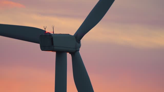 Close up detail of wind power turbine rotating rotor blades at breathtaking variegated cloudy sundown