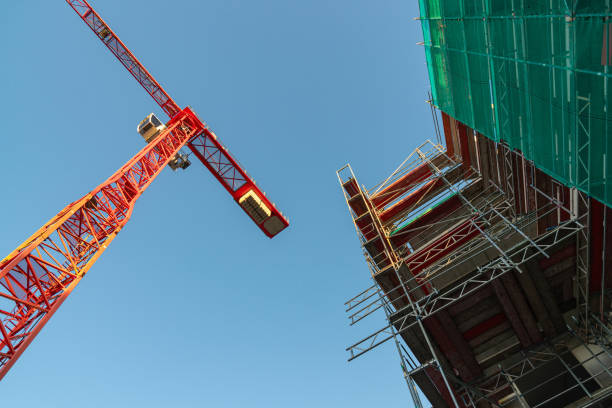 istock Bottom view of a tower crane and a house under construction surrounded by scaffolding. 1793530912