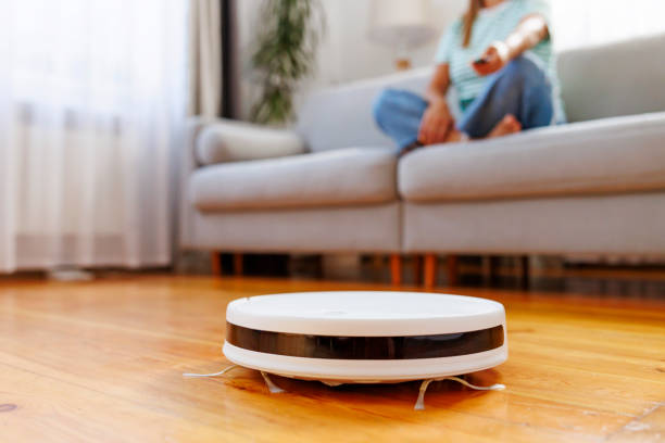 istock Robot vacuum cleaner cleaning a room while a woman relaxes on the sofa 1793532017