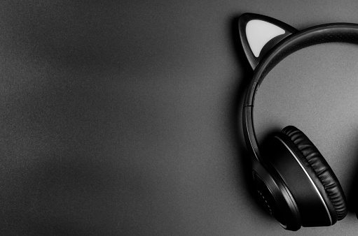 Black wireless headphones on a black background, copy space