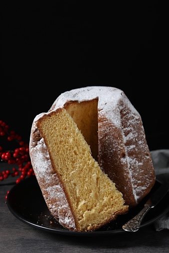 Delicious Pandoro cake with powdered sugar and decor on grey table. Traditional Italian pastry