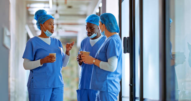 istock Scrub, nurses and masks or colleagues talking for healthcare problem, solution or medical patient. Diversity workers, coffee and discussion in corridor hallway for hospital planning, support or break 1793544203