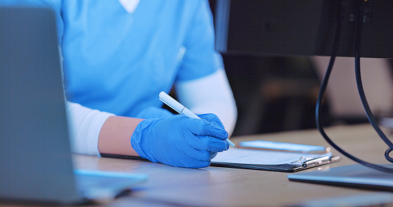 Nurse, hand and writing notes closeup at laptop for online information, healthcare paper or knowledge. Hospital worker, pen for internet search or diagnosis wellness or planning, document or research