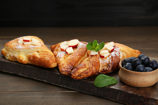 Fresh tasty puff pastry with blueberries, apples and mint served on wooden table