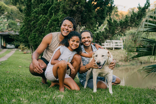 Portrait of gay couple with daughter and dog in the backyard