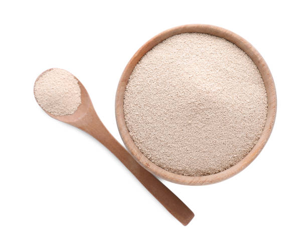 istock Bowl and spoon with active dry yeast isolated on white, top view 1793562442