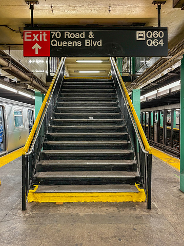 05/14/2023 - Queens, New York, NY, USA: Exit sign and stairs on subway platform in Forest Hills, Queens, New York City