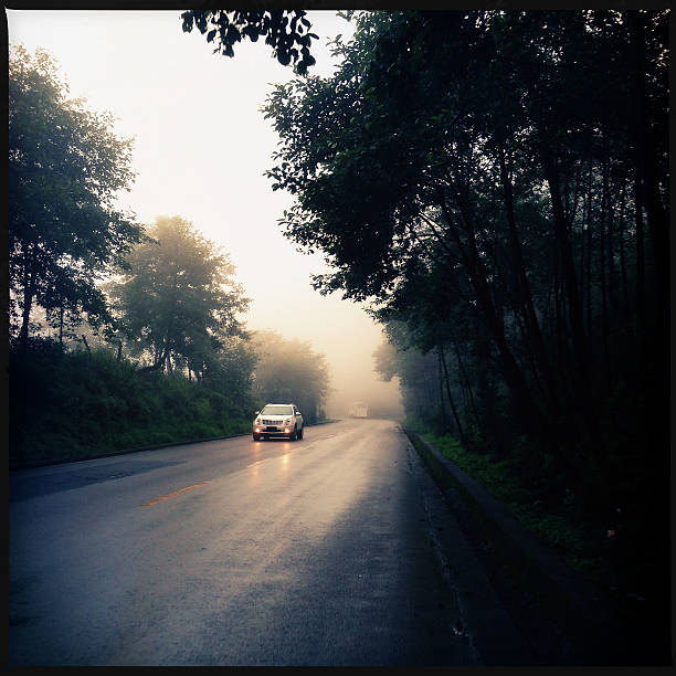 voiture conduite sur route de montagne - asphalt two lane highway natural phenomenon fog photos et images de collection