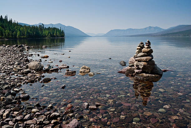Rock Cairn at Lake McDonald Lake McDonald is 10 miles long and over a mile wide making it the largest lake in Glacier National Park. It fills a deep valley formed by erosion and glacial activity. Lake McDonald is on the west side of the Continental Divide. The Going-to-the-Sun Road parallels the lake along its southern shoreline. The lake was photographed from Lake McDonald Lodge in Glacier National Park, Montana, USA. jeff goulden glacier national park stock pictures, royalty-free photos & images
