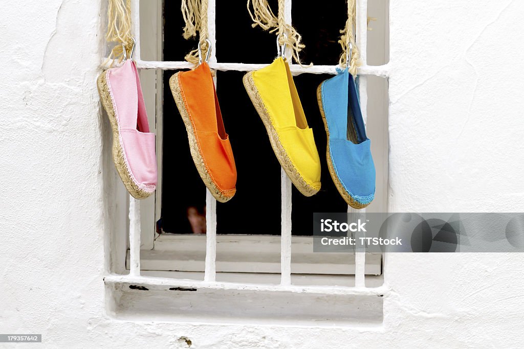 Four shoes hanging Four brightly colored traditional spanish shoes hanging outside a window Espadrilles Stock Photo