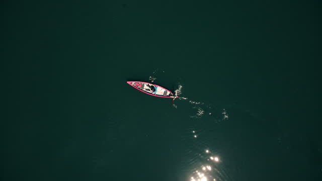 Aerial view of woman and kid canoeing on the lake. Shoot directly above