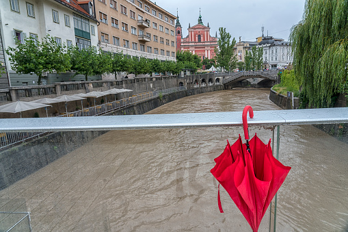 View on Ljubljanica river after heavy rain fall in center of LJubljana city. Red umbrella hanging from the bridge.