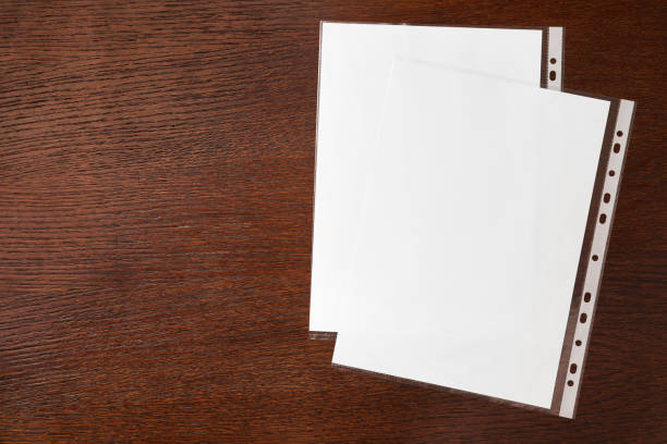 istock Punched pockets with paper sheets on wooden table, flat lay. Space for text 1793610618