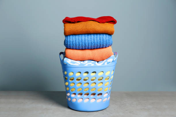 istock Plastic laundry basket and clean clothes on grey table 1793610638