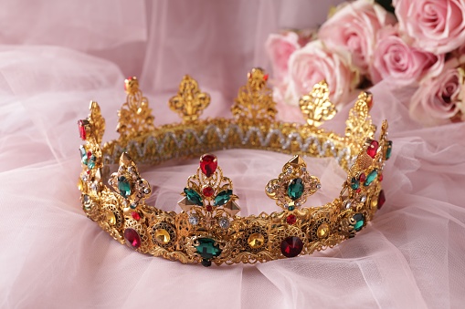 Beautiful golden crown with gems on pink cloth