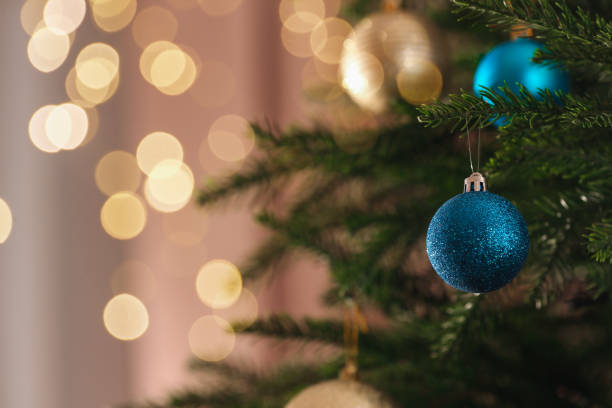 Christmas tree with beautiful baubles on blurred background, closeup. Space for text