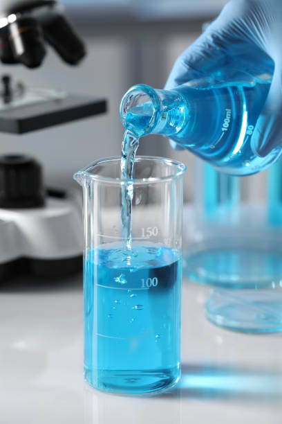 istock Scientist pouring light blue liquid from flask into beaker in laboratory, closeup 1793632597