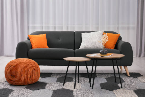 istock Comfortable sofa, pouf and coffee table in stylish room. Interior design 1793640640