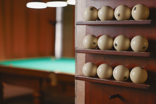 Set of billiard balls on wooden shelves indoors, closeup. Space for text