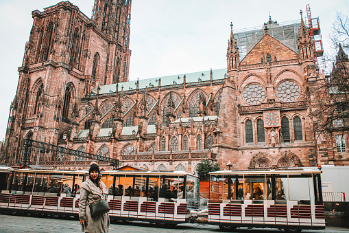 Image of a woman in the side of the cathedral of Strasbourg, with a Christmas market