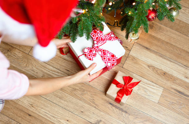istock A woman puts presents under a Decorated Christmas tree. 1793668653