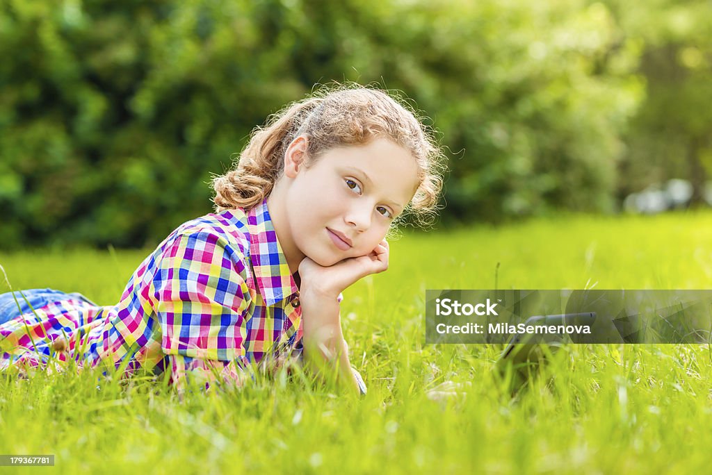 십대 여자아이 라잉 on 잔디 디지털 태블릿 또는 e-book - 로열티 프리 고등학교 이하 스톡 사진