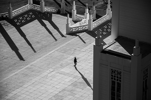 A woman is walking at the Cathedral of Our Lady of the Immaculate Conception in Maputo, Mozambique in the sunset light in Black and White.