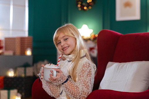 Portrait of an adorable little girl drinking a hot drink with whipped cream and marshmallows. Hot Chocolate to Keep Me Warm!