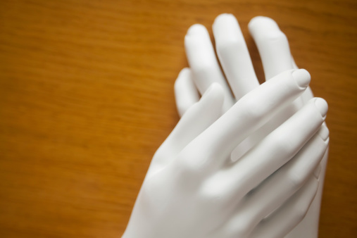 Mannequin hands on wooden surface expressing support.