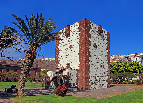 Gothic tower Torre del conde in San Sebastian de La Gomera, Gomera Island, Canary Islands, Spain - old Gothic tower with palm tree in the neighborhood, ocher brickwork with white plaster