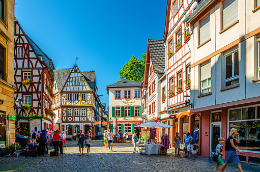 Mainz, Germany, August 24, 2019: Traditional german houses with typical wooden facade fachwerk style and tourists people walking down cobblestone square in historical medieval town centre