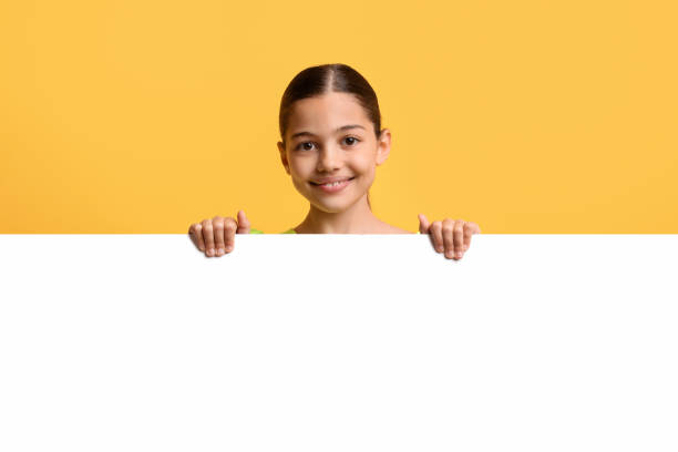 istock Adorable pretty middle eastern schoolgirl showing empty advertising board 1793747576