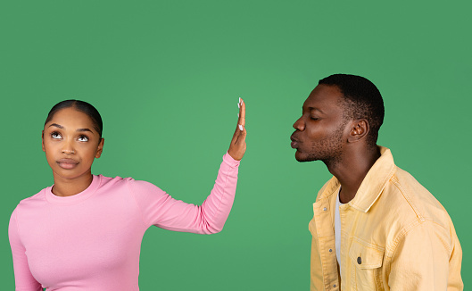 Young couple two friends black man and woman on green background. Guy try want kiss lady but she do stop palm gesture and does not want. Friend zone, friendship, relationships concept
