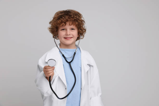 istock Little boy in medical uniform with stethoscope on light grey background. Space for text 1793755581