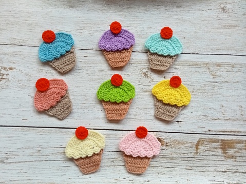 crochet cupcakes with cherry red, crocheted handmade in multicolor background texture