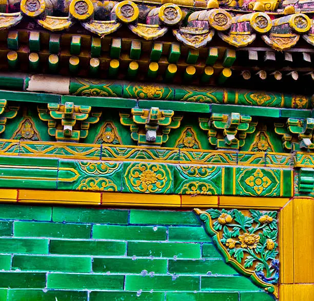 Details of a side of the building in The Forbidden City that has green and yellow tiles with flower design