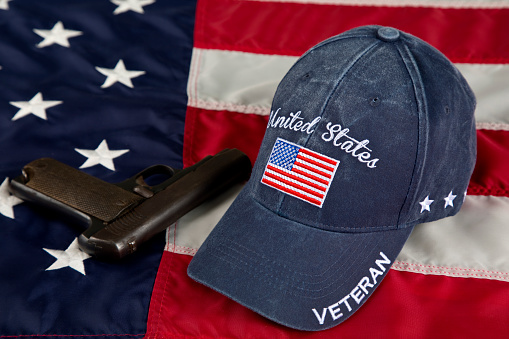 USA Second Amendment constitutional Right to Bear Arms. Antique firearm and veterans cap resting on an American Flag.