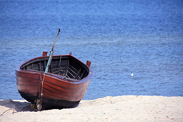 Old ruined wooden boat on the shore near the water and heap of oyster shells