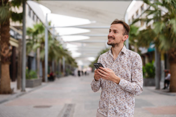 istock Handsome young man using his smart phone while walking in a city 1793830901