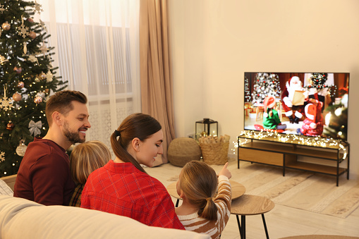 Happy family spending time together near TV in cosy room. Christmas atmosphere