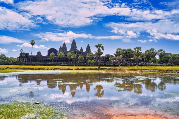 Angkor Wat Temple Complex reflected in the lake at mid day - UNESCO World Heritage 12th century masterpiece of Khmer Architecture built by Suryavarman II at Siem Reap, Cambodia, Asia