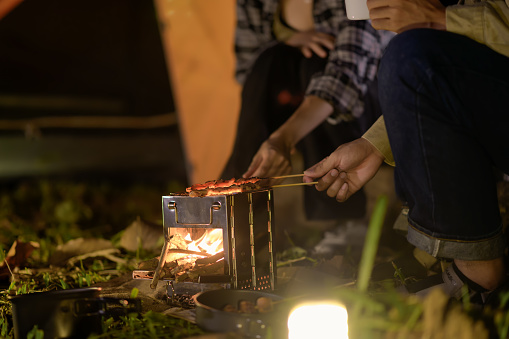 Close-up of barbecue meal grill in the wilderness of backpacker group. Grilled meals ready to eat for hiking groups, Camping in nature, Cooking at night with an atmosphere that is warm and inviting.